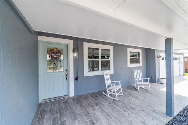 doorway to property featuring a porch and stucco siding