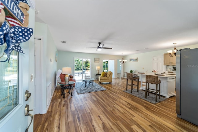 living room featuring ceiling fan with notable chandelier and wood-type flooring