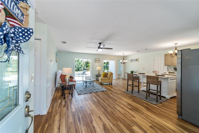 living room with wood finished floors, ceiling fan, and a chandelier