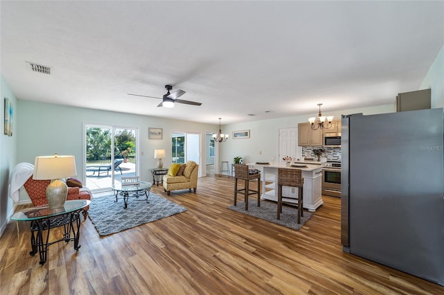 living room with ceiling fan with notable chandelier and hardwood / wood-style floors