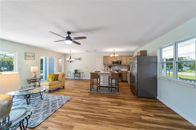 living area with a chandelier, wood finished floors, a ceiling fan, and baseboards