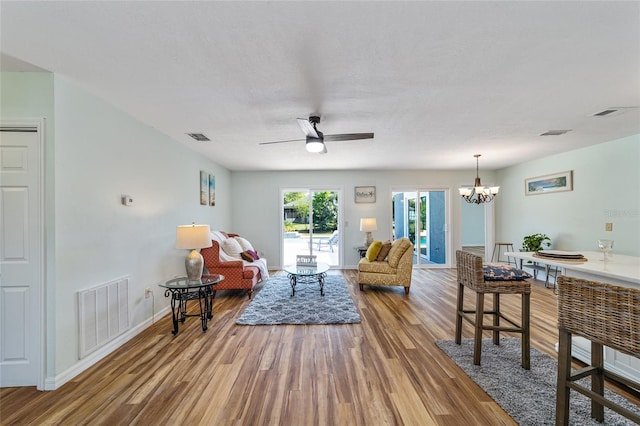 living room with ceiling fan with notable chandelier and wood-type flooring