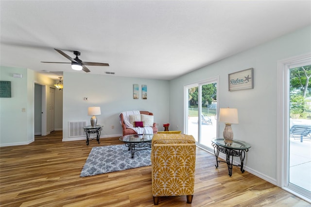 living room with light wood-type flooring, ceiling fan, and plenty of natural light