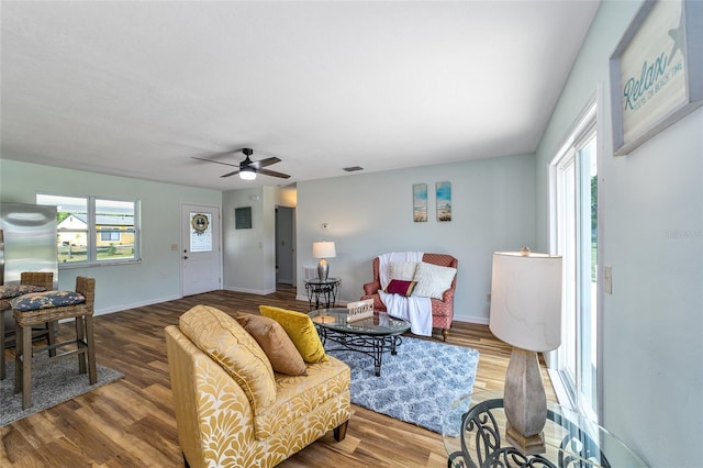 living area with wood finished floors, a ceiling fan, and baseboards