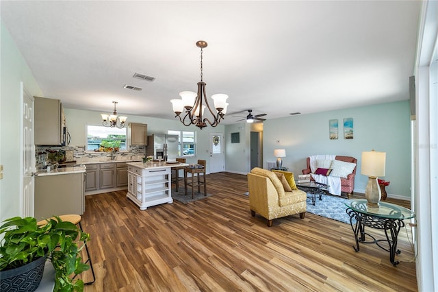 living room with ceiling fan with notable chandelier and dark hardwood / wood-style flooring