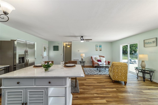 kitchen featuring stainless steel fridge, wood finished floors, ceiling fan, and a center island