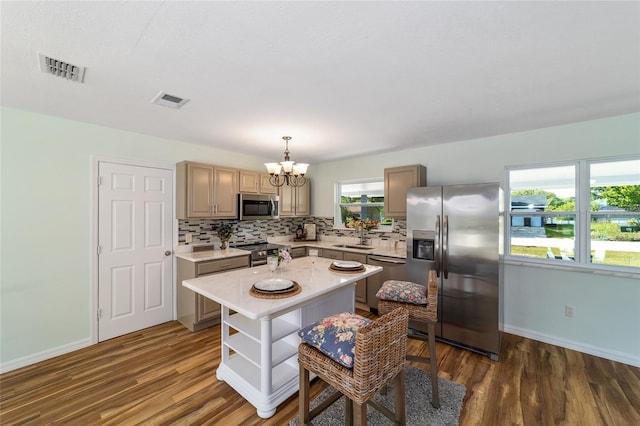 kitchen with stainless steel appliances, light countertops, wood finished floors, a chandelier, and tasteful backsplash
