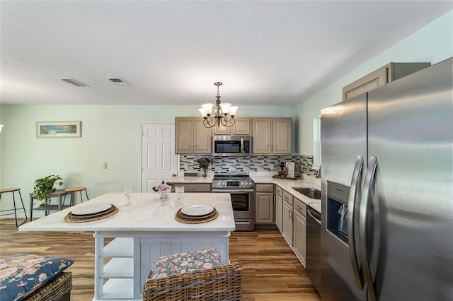 kitchen featuring pendant lighting, a notable chandelier, a kitchen island, dark hardwood / wood-style floors, and appliances with stainless steel finishes