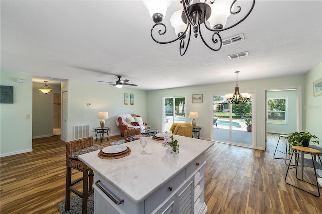 kitchen featuring ceiling fan with notable chandelier, dark hardwood / wood-style flooring, a kitchen island, and hanging light fixtures