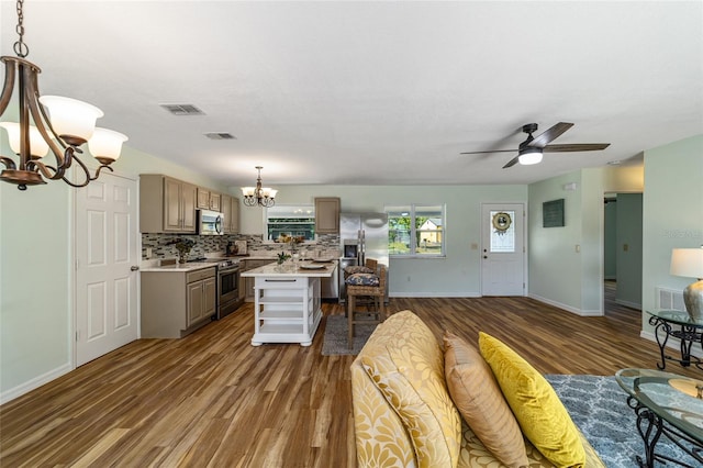 kitchen featuring ceiling fan with notable chandelier, stainless steel appliances, decorative light fixtures, a center island, and dark hardwood / wood-style floors