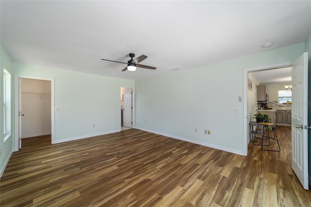 unfurnished room featuring dark wood finished floors, ceiling fan, baseboards, and a smoke detector