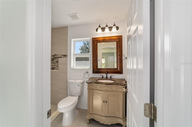 bathroom with toilet, vanity, and tile patterned floors
