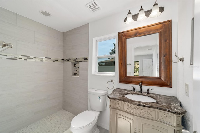 bathroom featuring vanity, toilet, and tiled shower