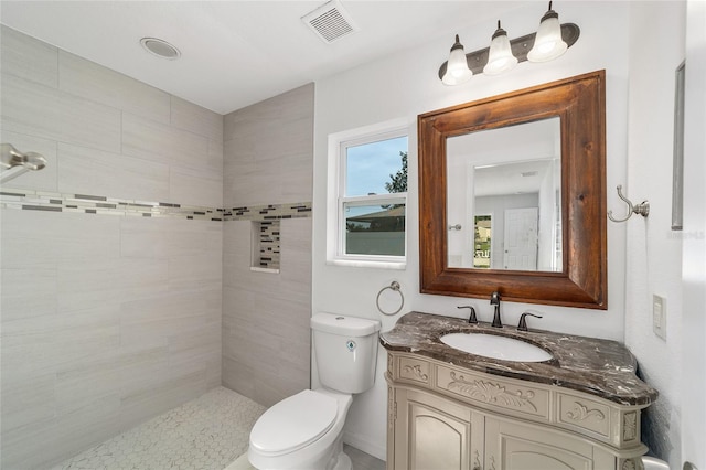 bathroom featuring toilet, vanity, and tiled shower