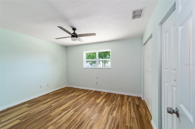 unfurnished bedroom featuring wood-type flooring, a textured ceiling, and ceiling fan