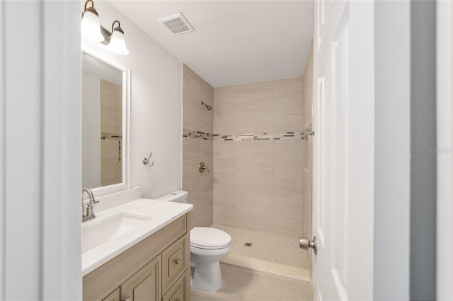 bathroom featuring vanity, toilet, and tiled shower