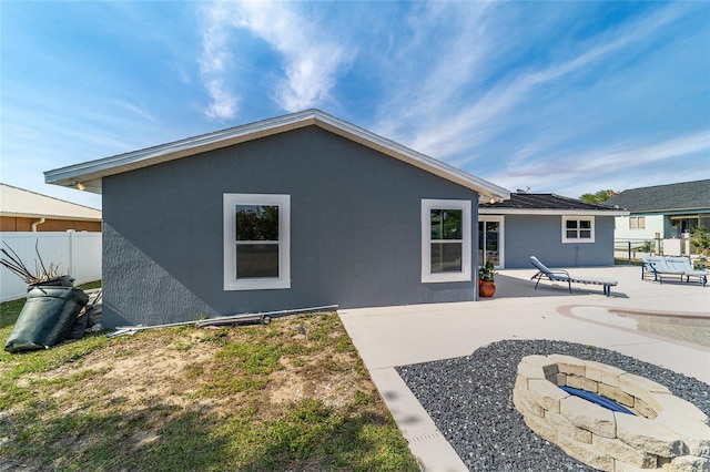 back of property with a fire pit, fence, a patio, and stucco siding