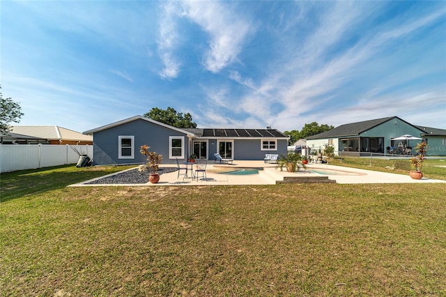 back of property with a patio area, solar panels, a yard, a fenced in pool, and a sunroom