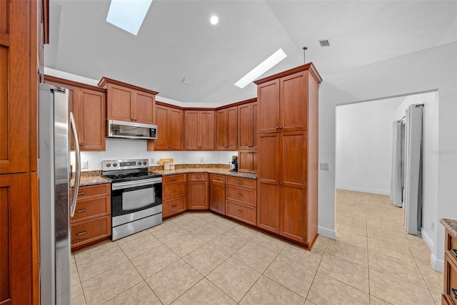 kitchen featuring light tile patterned floors, light stone counters, lofted ceiling with skylight, and appliances with stainless steel finishes