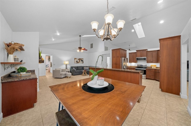 tiled dining space featuring vaulted ceiling with skylight and ceiling fan with notable chandelier