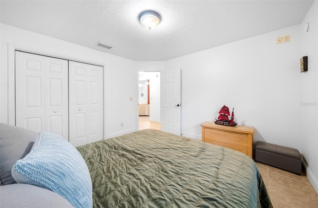 tiled bedroom with a textured ceiling and a closet