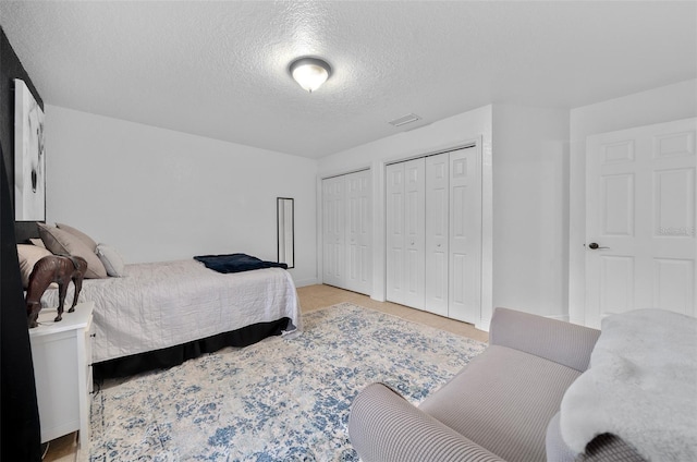 bedroom with a textured ceiling and two closets