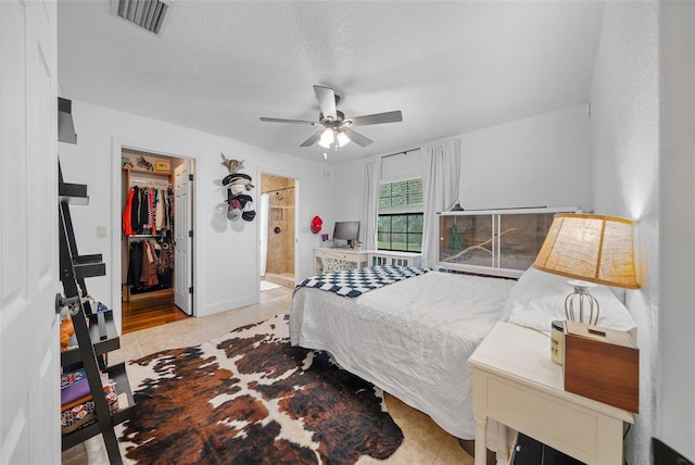 bedroom with a textured ceiling, ceiling fan, a spacious closet, connected bathroom, and a closet