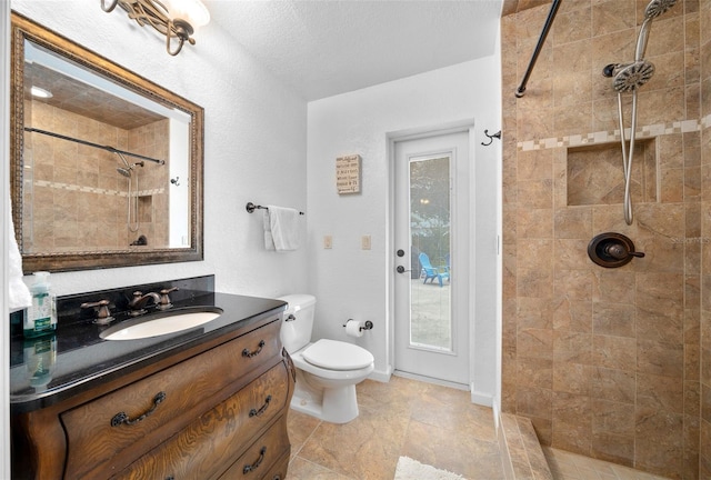 bathroom featuring vanity, tile patterned flooring, toilet, a textured ceiling, and tiled shower