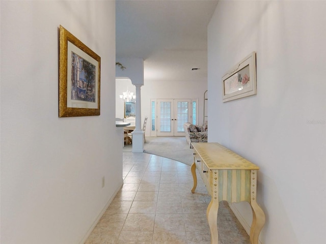 corridor featuring decorative columns, light tile patterned floors, and french doors