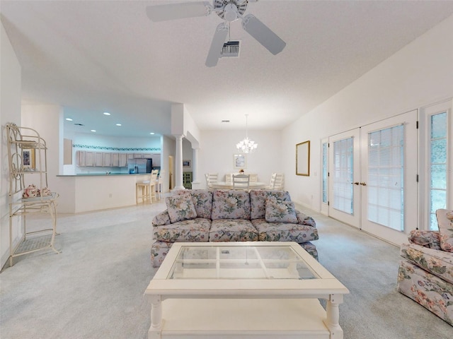 carpeted living room with ceiling fan with notable chandelier and french doors