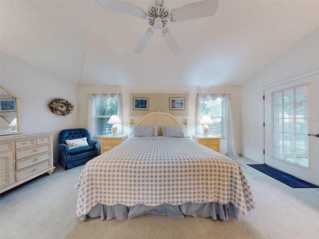 carpeted bedroom with a textured ceiling, vaulted ceiling, multiple windows, and ceiling fan