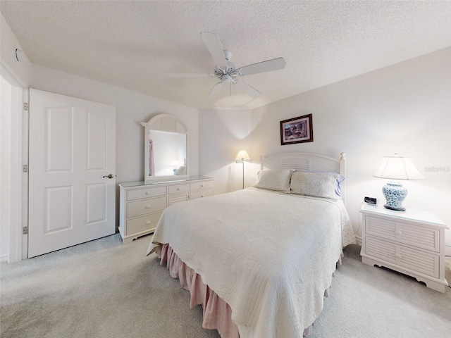 bedroom with a textured ceiling, light colored carpet, and ceiling fan