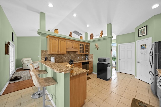 kitchen featuring appliances with stainless steel finishes, a wealth of natural light, kitchen peninsula, a kitchen bar, and tasteful backsplash