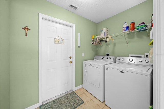 laundry area featuring light tile patterned floors, independent washer and dryer, and a textured ceiling