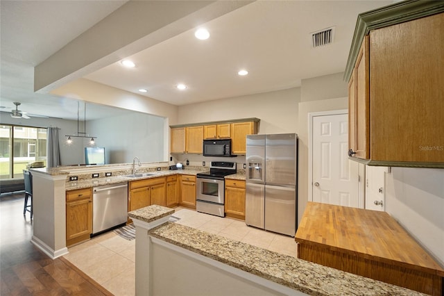 kitchen with light wood-type flooring, stainless steel appliances, kitchen peninsula, ceiling fan, and pendant lighting