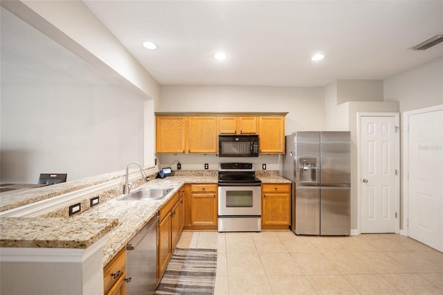 kitchen featuring light tile patterned floors, stainless steel appliances, light stone counters, kitchen peninsula, and sink