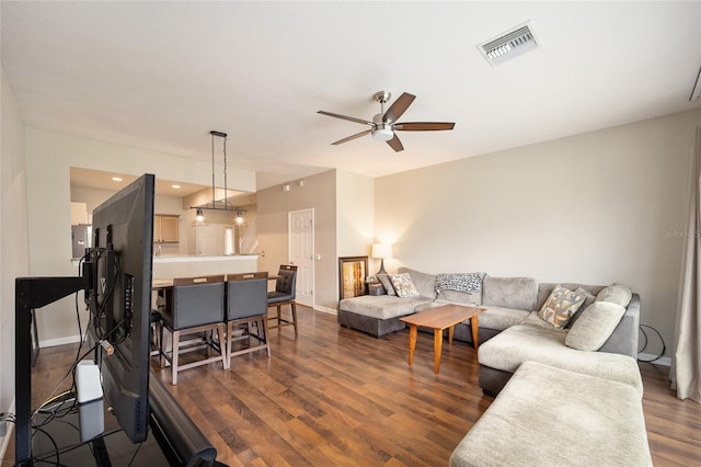 living room featuring ceiling fan and dark hardwood / wood-style floors