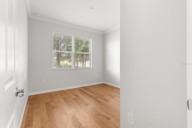 unfurnished room featuring ornamental molding, light wood finished floors, a textured ceiling, and baseboards