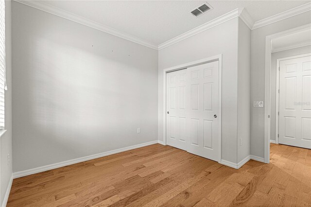 unfurnished bedroom featuring light wood-type flooring, ornamental molding, and a closet