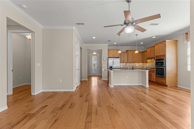 kitchen featuring open floor plan, stainless steel appliances, light wood finished floors, and visible vents