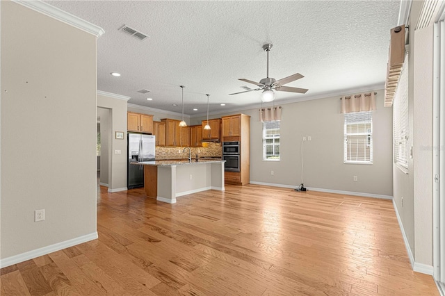 kitchen with hanging light fixtures, stainless steel appliances, crown molding, a breakfast bar area, and a center island with sink