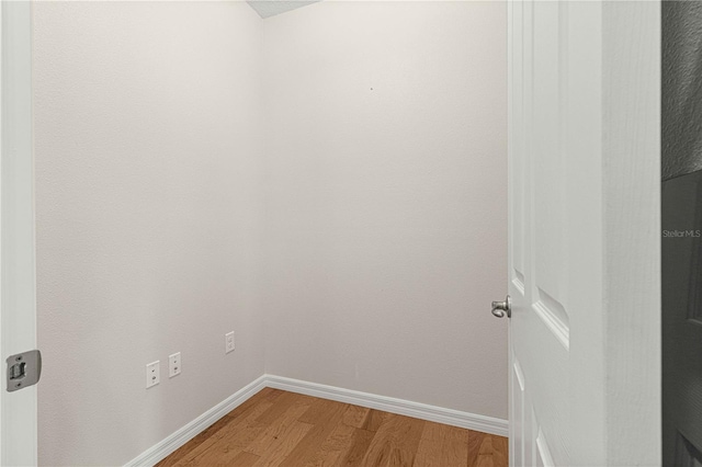 clothes washing area featuring light wood-style floors and baseboards