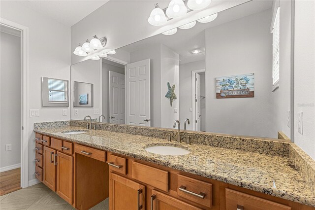 full bath with tile patterned floors, a sink, baseboards, and double vanity