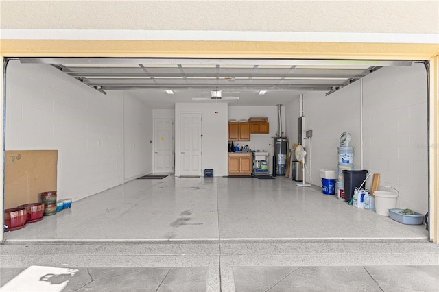 garage with concrete block wall, gas water heater, and a garage door opener