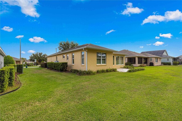 back of house featuring a lawn and stucco siding