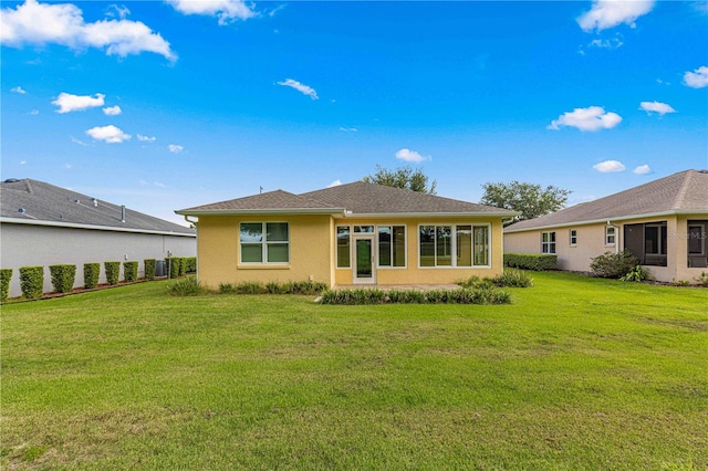 back of house featuring stucco siding and a yard