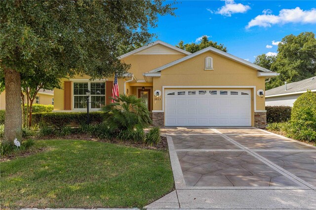 view of front of property featuring a garage, a front yard, concrete driveway, and stucco siding