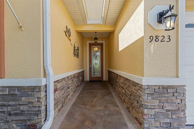 view of exterior entry featuring stone siding, brick siding, and stucco siding