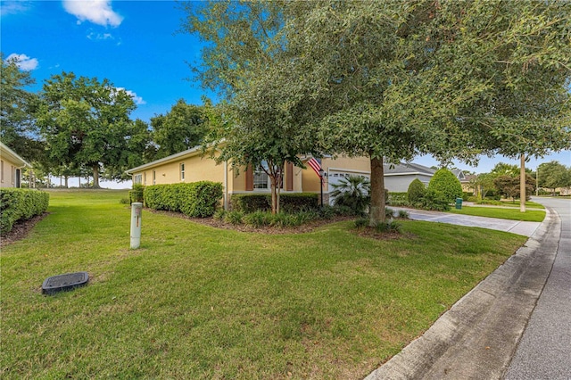 view of front of house featuring driveway, stucco siding, and a front yard