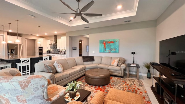 living room with ceiling fan, a raised ceiling, and ornamental molding